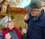 A happy elderly couple sharing a joyful moment on a swing in autumn setting.